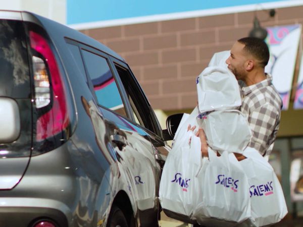 man carrying bags from restaurant to his car